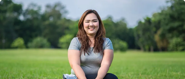 mujer de mediana edad sentado en un parque posando para una fotos y vistiendo una blusa color gris y pantalón negro